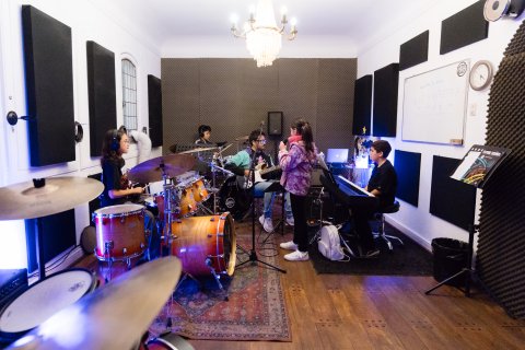 Taller de banda: batería, guitarra, voz y teclado tocando juntos